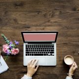 女性がパソコンの前でコーヒーを持つ画像